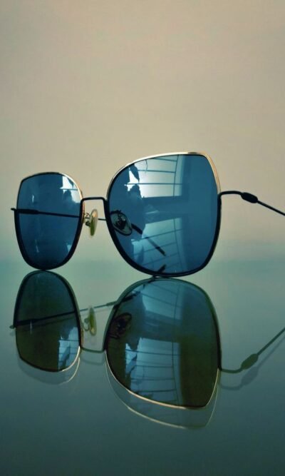 Close-up of modern sunglasses with reflective lenses on a smooth surface.